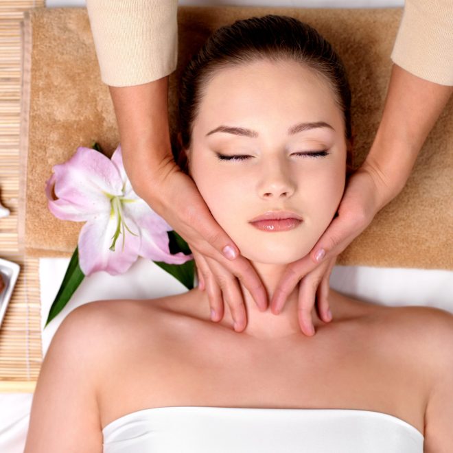 Beautiful young girl getting massage for neck in spa salon - indoors