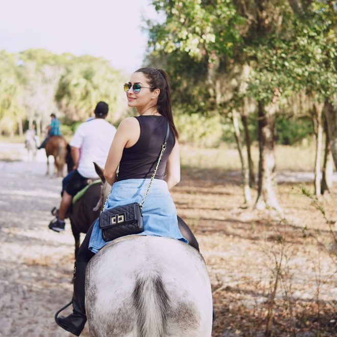 girl in sunglasses walking on the farm with horses